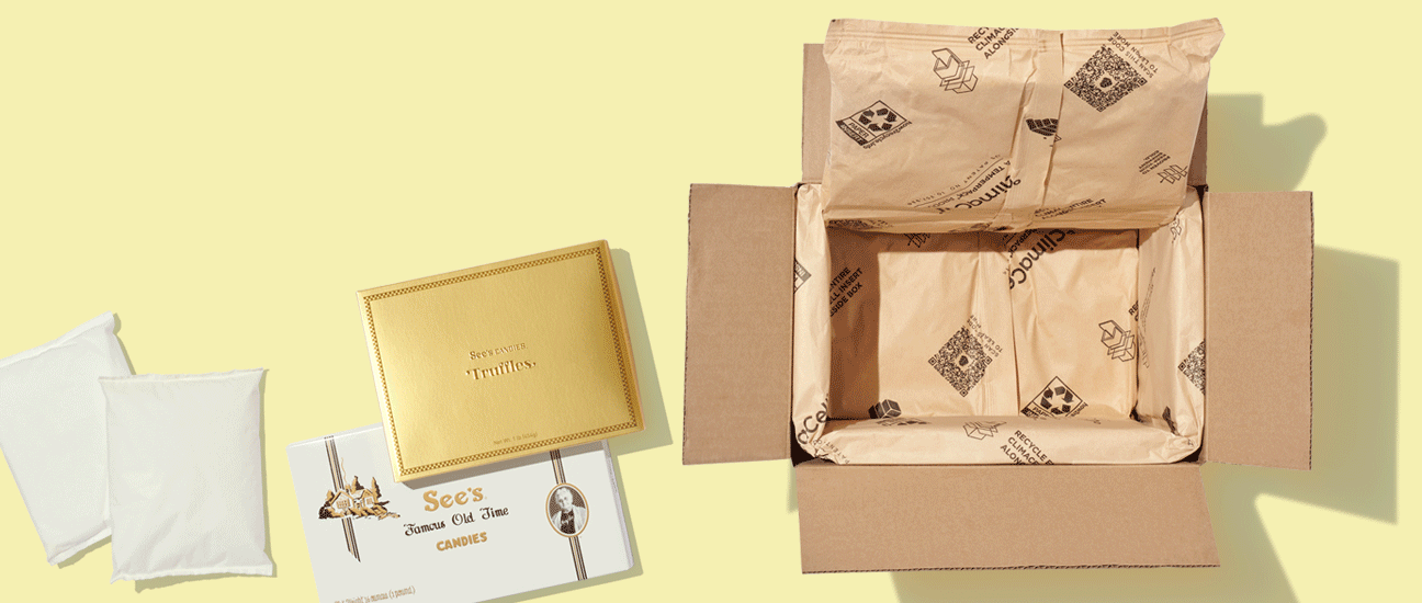 An insulated shipping box next to a box of truffles and assorted chocolates and some ice packs